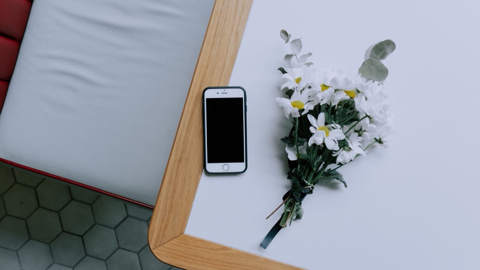 Smartphone lying on a table beside a small bunch of white flowers
