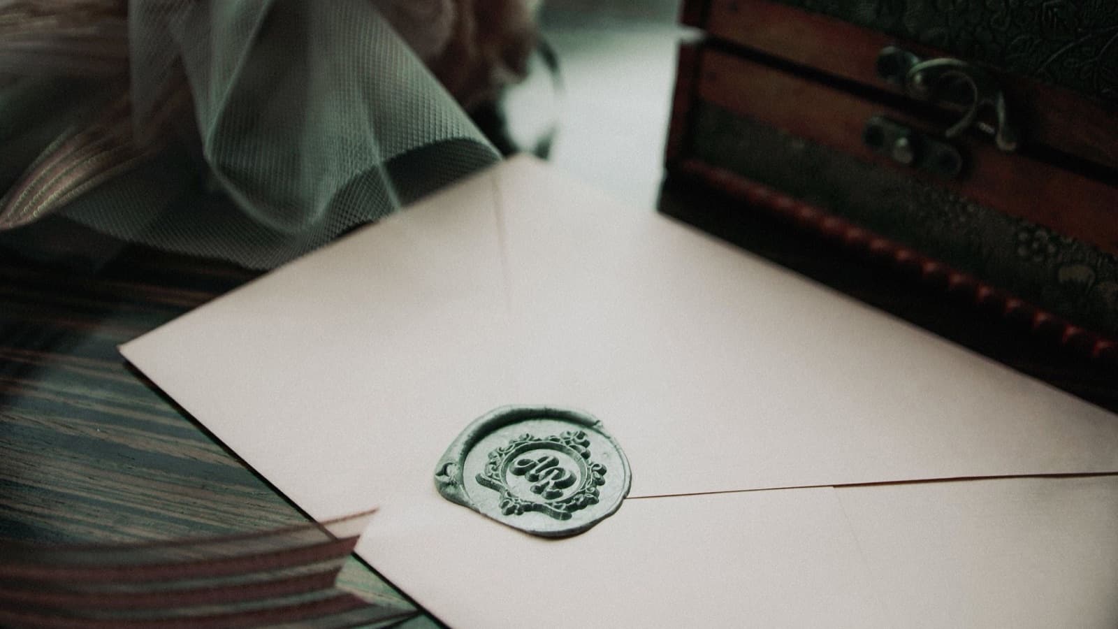 Printed wedding invitation envelope closed with a green wax seal